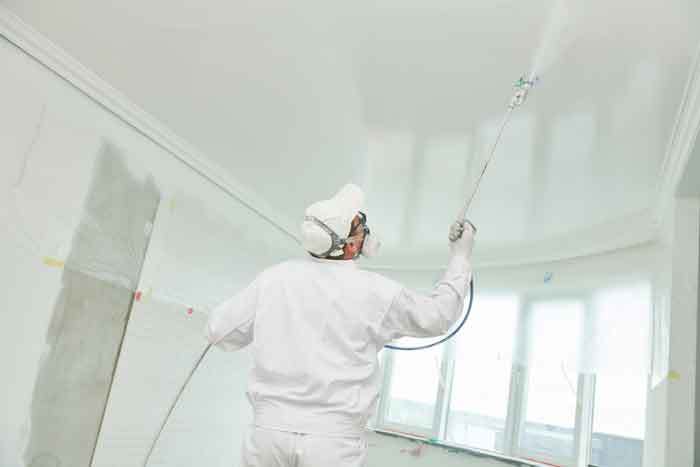 man spray painting ceiling