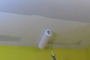 photo rolling white paint onto a ceiling