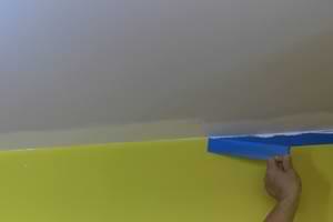 photo pulling masking tape off a wall after painting