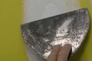 photo using a joint knife to smooth out drywall paper fibers