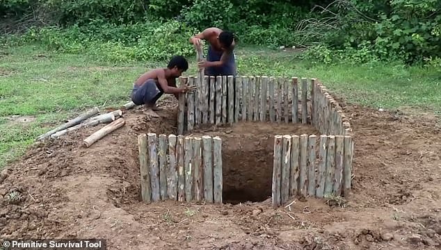 The house is created using logs, which are driven into the ground in the space the two men have dug out