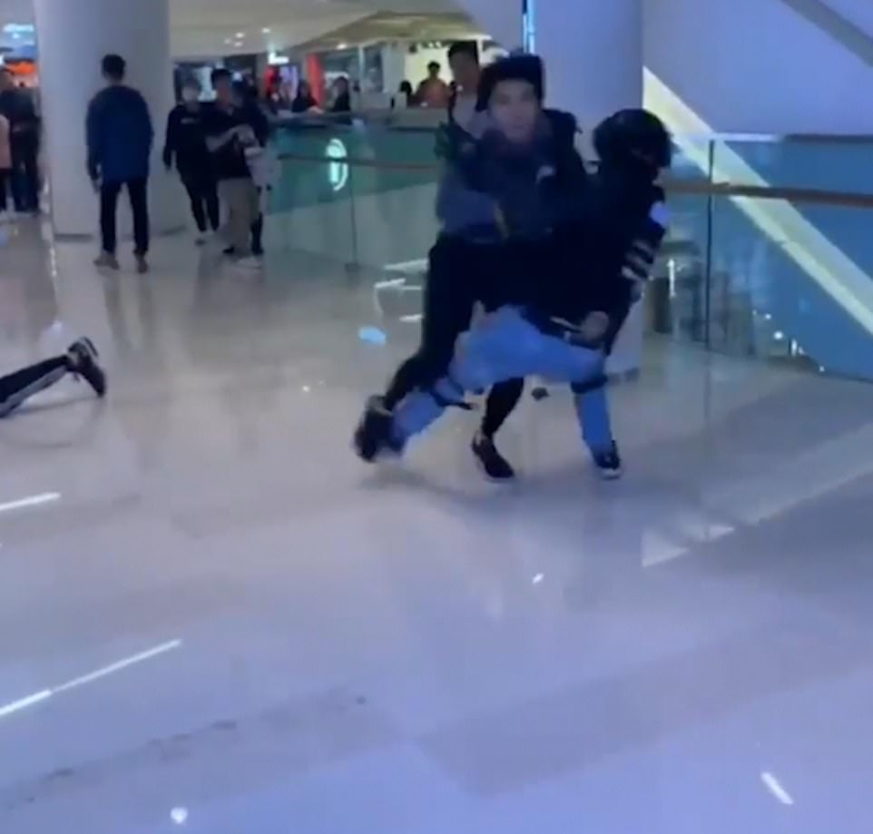 The man pushes passed an officer and  sprints across the second floor of Yuen Long mall in Hong Kong on Christmas Eve