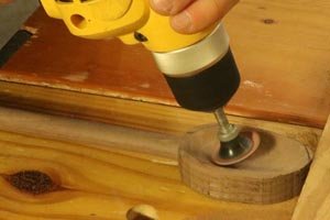 Using a drill to sand the bowl on a wooden spoon.