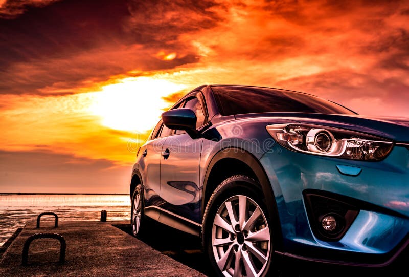 Blue compact SUV car with sport, modern, and luxury design parked on concrete road by the sea at sunset. Front view of beautiful royalty free stock images