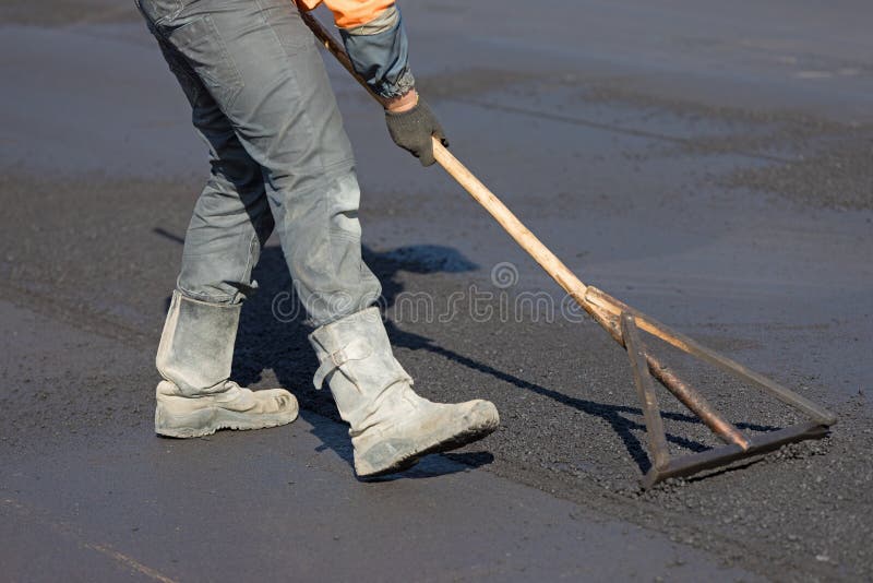 Construction road worker levelling fresh asphalt concrete stock images